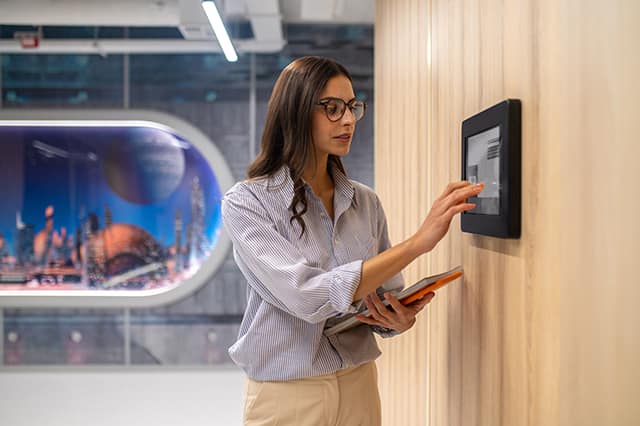 woman touching control panel on wall in corridor woman touching control panel on wall in corridor